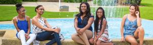 Five orthodontic treatment patients with braces sitting on a fountain