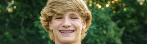 Teen with metal braces smiling outside